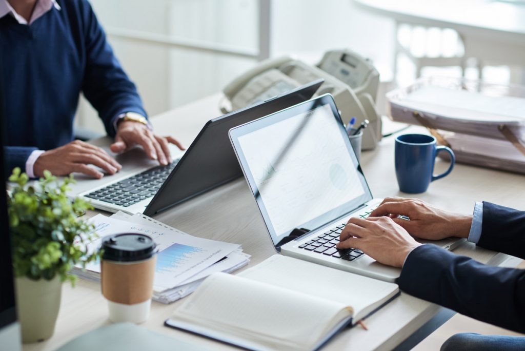 Cropped image of business people working on laptops in office.